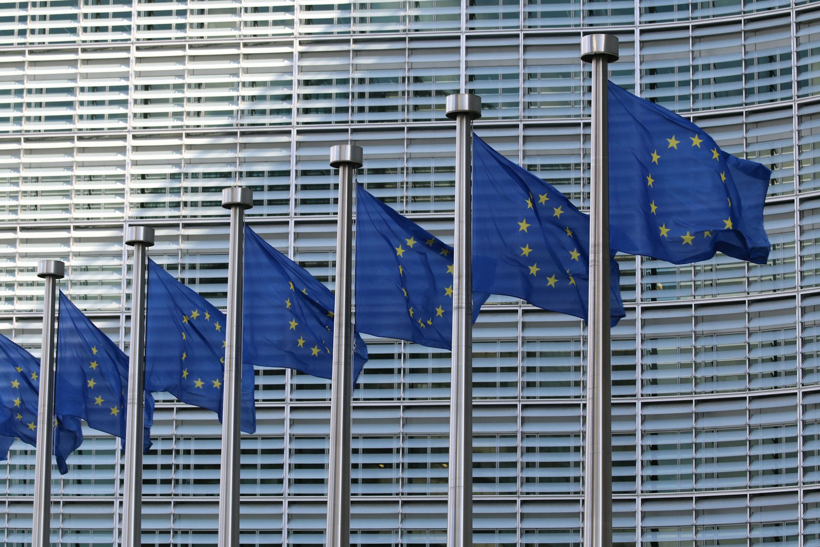European Union flags waving in front of an EU institutional building.